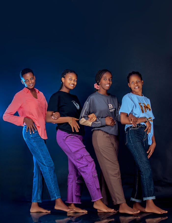 A group of four fashionable young adults posing confidently against a dark background.